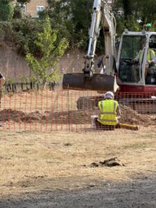Excavator with archaeologists at Brightling Road Leisure Ground