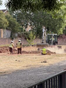 Excavator with archaeologists at Brightling Road Leisure Ground