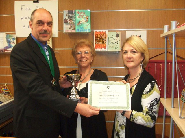 Mayor malcolm cunningham presents the best christmas lights cup to the staff of the salvation army shop