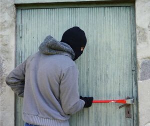 Masked man with a crowbar attempting to break into a door
